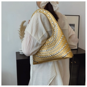 Sac croissant doré chic à rivets argentés porté par un mannequin dans un cadre minimaliste