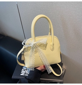 Détail du sac à main jaune en cuir grainé orné d'un nœud en dentelle blanche