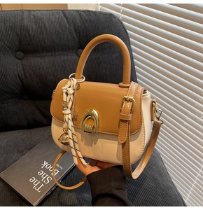 Close-up of saddle bag with gold metal buckle, striped scarf charm and key detail