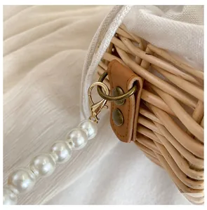 Close-up of woven rattan bucket bag with white drawstring liner and pearl chain strap