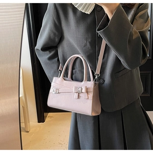 Detail of pink glossy leather crossbody bag with bow decoration on a fashion model