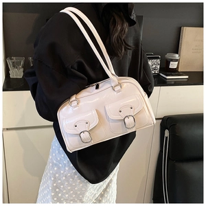 Model wearing a large cream-white pillow bag with dual front pockets and silver buckles