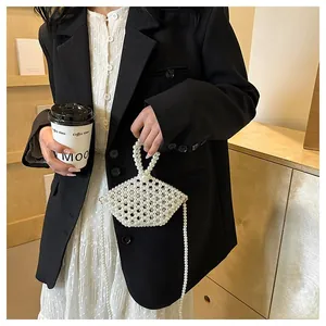 Detail of handmade pearl beaded crossbody bag with elegant ring handle and long chain strap
