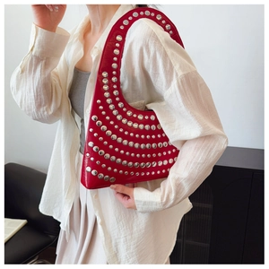 Détail du sac bandoulière rouge brillant avec clous métalliques argentés et design moderne