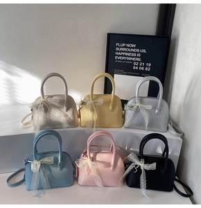 Détail de sacs Boston en six couleurs avec nœuds en dentelle sur présentoir blanc