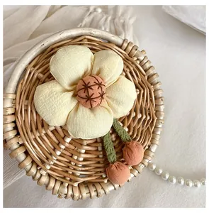 Detail of woven straw bag with floral fabric ornament and delicate pearl chain strap