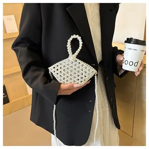 Detail of handmade white pearl beaded bag featuring round top handle and long chain strap
