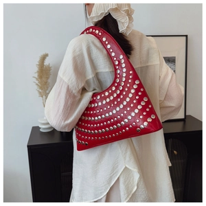 Détail du sac à bandoulière en cuir rouge avec rivets métalliques et style hobo chic
