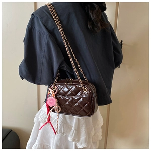 Detailed shot of dark brown quilted crossbody bag with gold chain and floral charm
