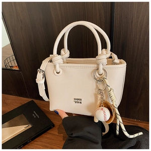 Close-up of cream mini tote bag with litchi texture and baseball theme accessory