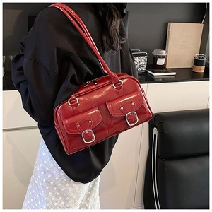 Detail of dark red patent leather shoulder bag featuring silver buckle front pockets