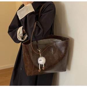 Detailed texture of brown vintage tote bag with a white fluffy monster charm detail