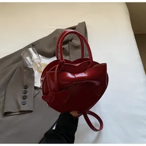 Detailed view of red heart-shaped bag with a large bow on a grey suit jacket