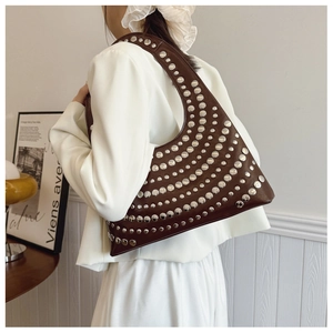 Détail d'un sac baguette en cuir verni marron avec clous argentés et forme en croissant