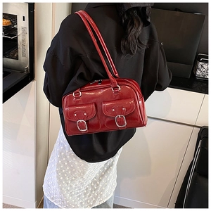 Detail view of a large red patent leather shoulder bag with vintage silver buckle pockets