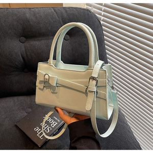 Detail of mint green handbag featuring decorative bow and adjustable metallic strap buckle
