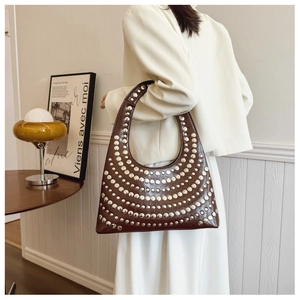Détail du sac hobo en cuir marron foncé avec des clous argentés dans un style rétro chic