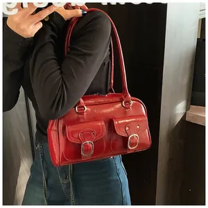 Close-up of a red patent leather handbag featuring dual front pockets and metallic buckles