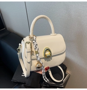 Close-up of cream leather handbag with gold buckle and decorative floral silk scarf