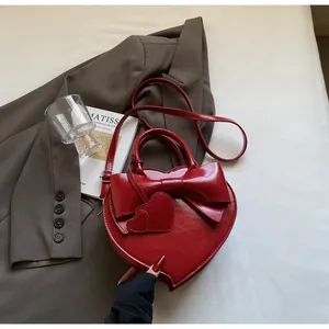 Macro detail of red heart-shaped bag featuring a large bow and shiny finish