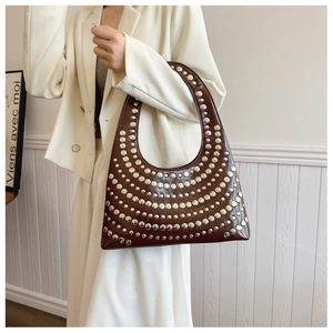 Sac hobo marron à rivets argentés porté par un mannequin en tailleur beige style rock