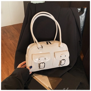 Close-up of cream glossy patent leather pillow bag with double front buckle pockets