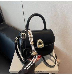 Detail of black saddle bag featuring gold horseshoe buckle and woven rope bell charm
