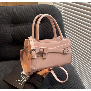 Detail of pink PU leather handbag showing bow decoration and adjustable shoulder strap