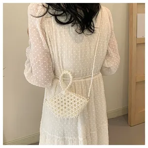 Handmade pearl beaded bag with a round handle shown from a back view on a model