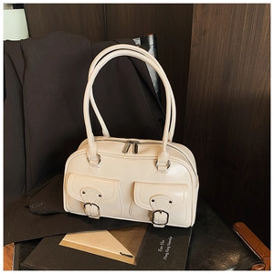 Detail view of cream-colored pillow bag with decorative pockets and silver metal buckles