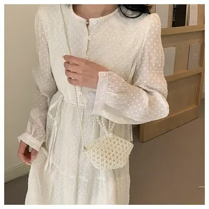 Detail of white handmade pearl beaded crossbody bag styled with a polka dot dress