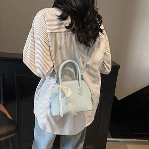 Sac à main bleu clair en forme de coquillage avec nœud en dentelle blanche et texture cuir