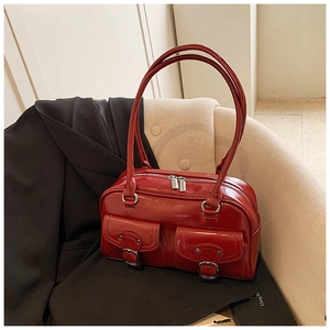 Detail view of dark red patent leather handbag featuring dual silver buckle pockets