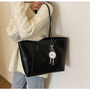 Black large capacity tote bag with plush doll pendant worn with white knit sweater