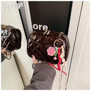 Detail of brown quilted crossbody bag with golden chain and colorful charm mirror view