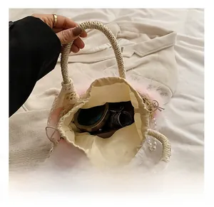 Detail view of woven straw bucket bag showing inner capacity and feather trim