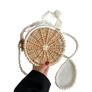 Handcrafted circular woven bag featuring elegant pearl chain strap and drawstring lining