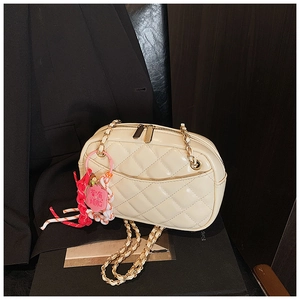 Close-up of beige quilted crossbody bag with double zippers and metal chain strap