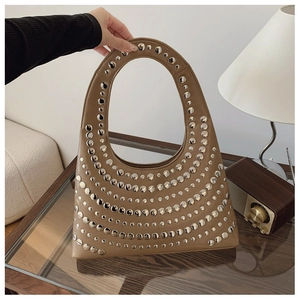 Détail d'un sac à main kaki orné de rivets argentés et doté d'une poignée circulaire
