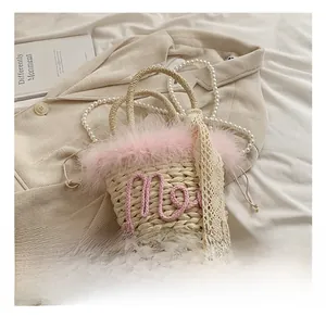 Detail of woven straw bucket bag featuring pink feathers and elegant pearl chain
