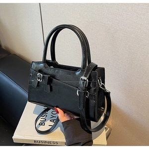 Detail of black leather handbag with decorative bow, vintage buckle and dual handles