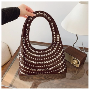 Détail d'un sac à main en cuir verni marron foncé avec rivets métalliques argentés