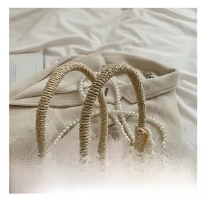 Detail of woven straw bag with pink feathers, white lace trim and pearl chain strap