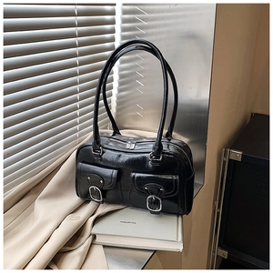 Close-up of black patent leather shoulder bag with silver buckles and zipper details