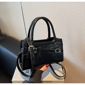 Detail of black faux leather tote bag with silver buckle and elegant bow decoration