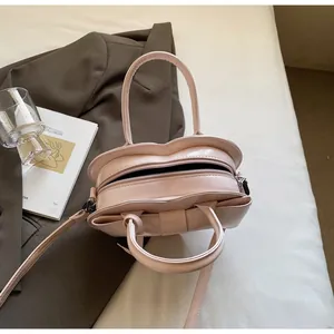 Detail view of pink heart-shaped patent leather crossbody bag on elegant attire