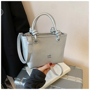 Detail of silver bucket bag with lychee texture and creative knotted handle design
