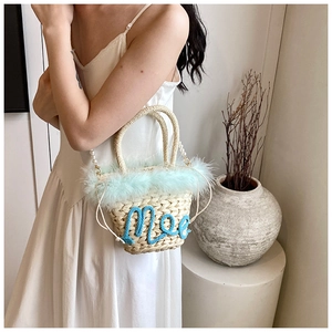 Detail of straw woven bag with light blue feather trim and pearl bead shoulder strap