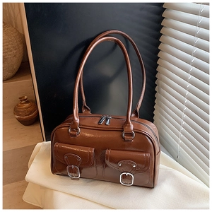 Detail of glossy brown faux leather handbag with silver buckles and flap pockets