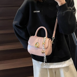 Pink saddle handbag with gold horseshoe buckle and woven strap on wood stairs